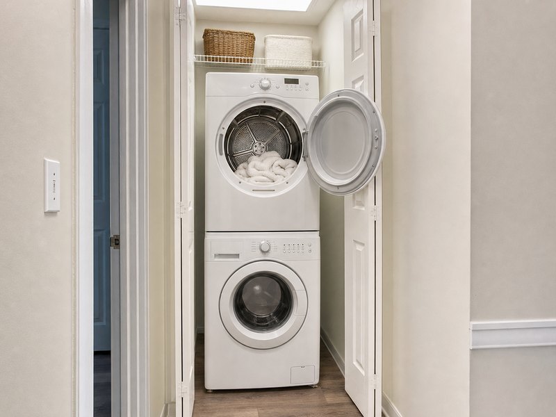 Stacked dryer and washer in a laundry closet, dryer door open with towels inside