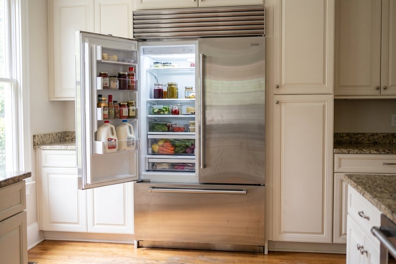 Built-in refrigerator with one door open, shelves stocked with food