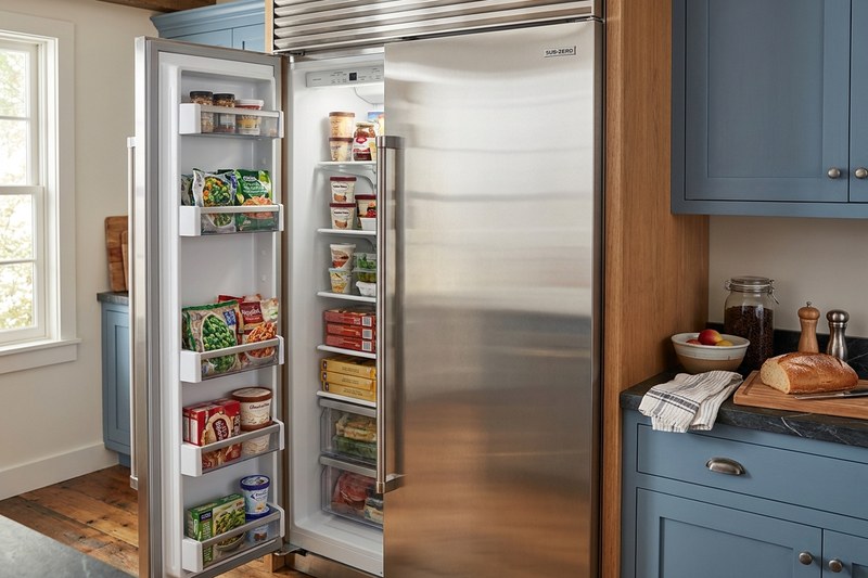 Side-by-side refrigerator with one door open, shelves fully stocked